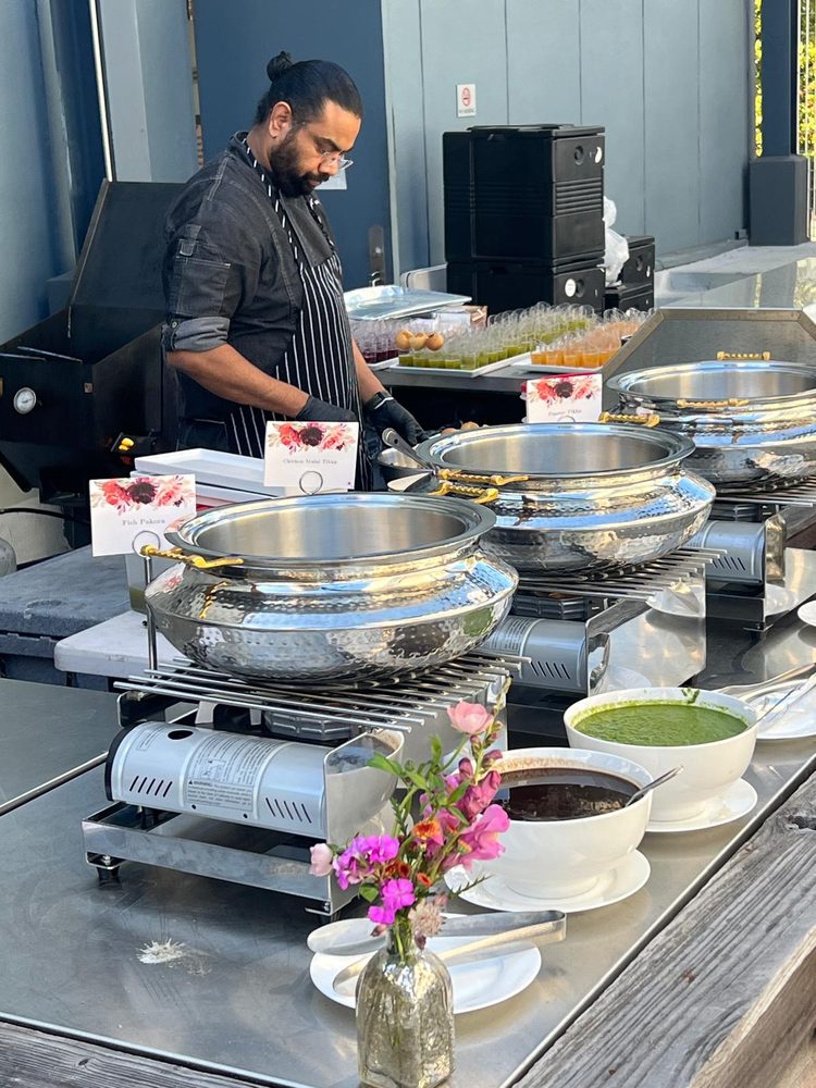 Chef plating Chicken Malai Tikka and Fish Pakora at an outdoor catering station