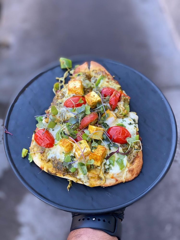 Indian-spiced flatbread topped with paneer, cherry tomatoes, and microgreens