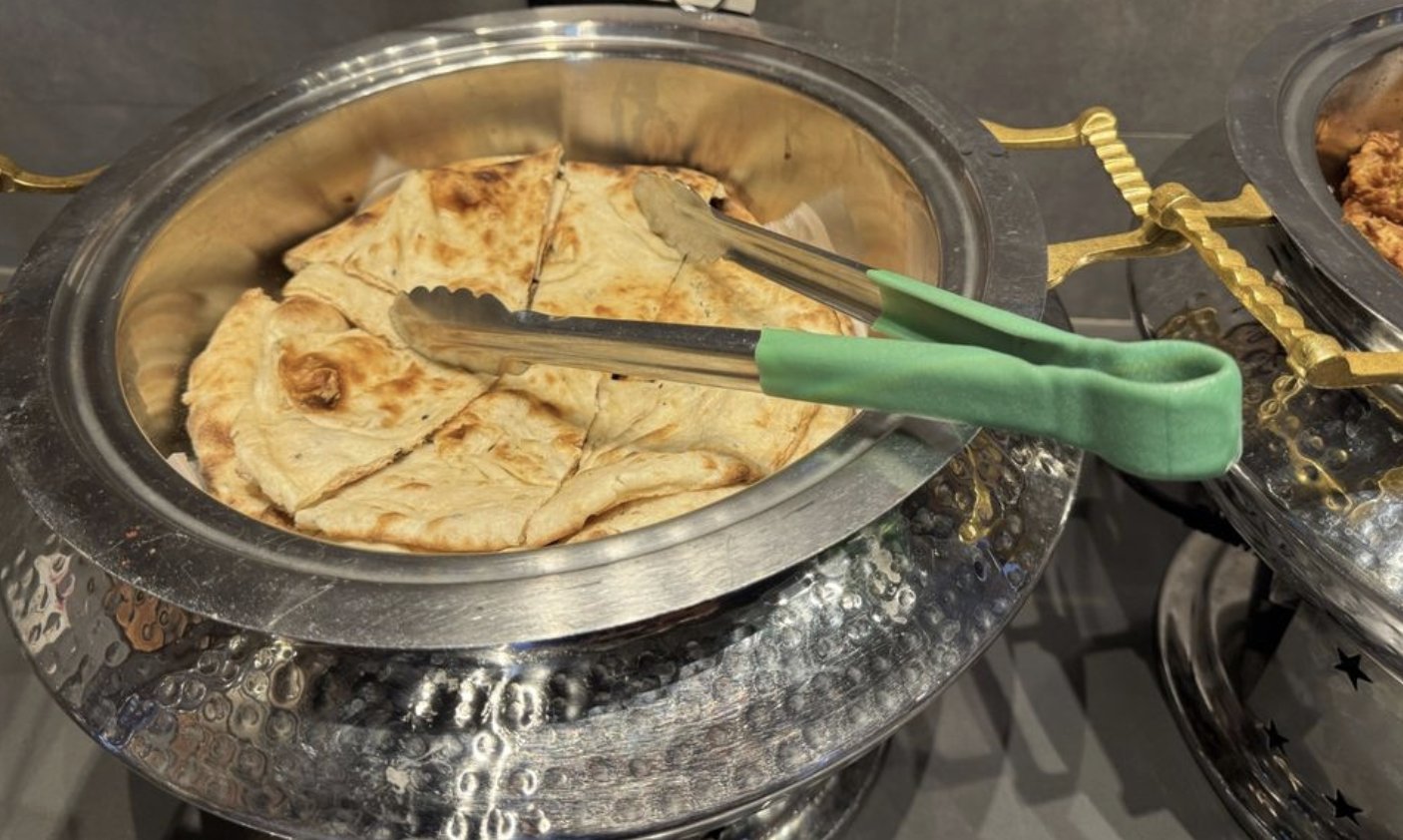 Fresh naan bread sliced and served in a chafing dish with tongs