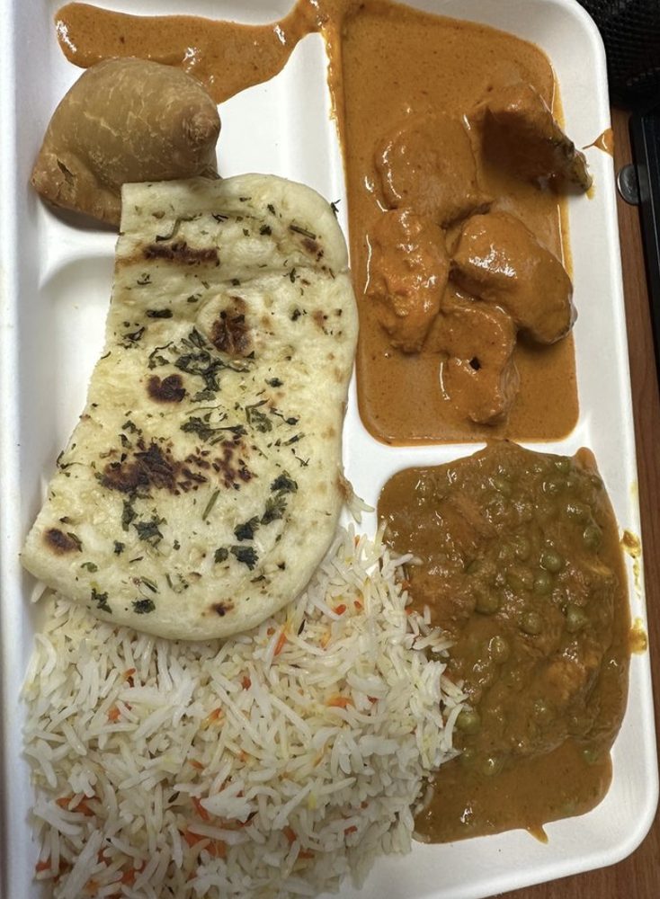 Office lunch tray with naan, rice, chicken curry, and dal